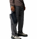 Person wearing grey hiking pants & shoes showing the packed Columbia Trailborne waterproof jacket for men in their hand.