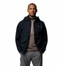 Man wearing a black jacket with a visible brand logo on a white background