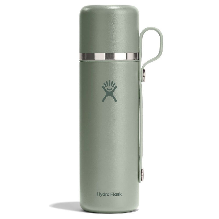 A Hydro Flask 28 oz (828 ml) Hot Flask & Cup in sage green, featuring a handle and a silver band near the top with vacuum insulation, stands upright on a white background.