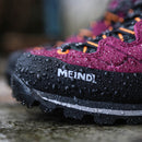 Close-up of a purple and black hiking shoe with 'MEINDL' branding on a stone surface.
