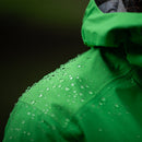 Green raincoat with beading water droplets on a dark background