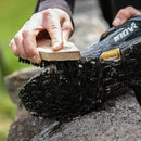 Person cleaning a black shoe with a grangers footwear cleaning brush outdoors