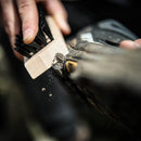 Person cleaning a boot with a grangers brush