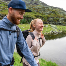 Man & Woman hiking beside a lake wearing helly hansen first layer tech tees.