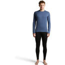 A man wears a blue long-sleeved Icebreaker Men’s Merino 260 Tech Long Sleeve Crew base layer and black leggings for cold-weather layering.