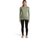 A woman wearing an Icebreaker Women’s Merino 260 Tech Long Sleeve Crew in sage green and black leggings.