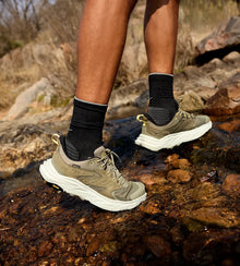 Person wearing HOKA hiking shoes and socks on a rocky trail