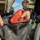 A person in an outdoor jacket puts a small red Leatherman® Tool Pouch by Leatherman into the side pocket of a black camo bike bag made from rPET ripstop nylon with weather-resistant zippers.