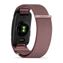 A close-up of the back of a Garmin CIRQA Smart Band with a pink woven strap. The sensor light is illuminated, and the Garmin logo appears on the clasp—emphasizing its 24/7 health monitoring capabilities in this sleek, screenless fitness tracker.
