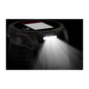 A black Garmin fēnix 9 multisport GPS smartwatch with a round face and rugged design emits a bright white light from its side, illuminating the dark background. The vibrant AMOLED display features a screen with a red-outlined battery icon, highlighting the advanced capabilities of this device.