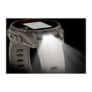 A close-up of the Garmin fēnix 9 multisport GPS smartwatch with a white strap, highlighting its bright LED flashlight on the side. The light is switched on, illuminating the strap and surrounding area against a black background.