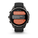 The Garmin fēnix 9 Pro inReach multisport GPS smartwatch, featuring a black band and multiple side buttons, displays a text conversation about travel plans and messaging upon arrival at camp. With its advanced satellite connectivity, it keeps you connected off the grid.
