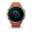 A Garmin fēnix 9 Pro inReach multisport GPS smartwatch with an orange band displays a screen featuring a white phone and microphone icon inside a blue glowing play button.