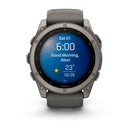 A Garmin fēnix 9 multisport GPS smartwatch displays the time as 6:00, shows the date Sat 01, and greets with “Good Morning, Alex!”. The screen features a sun icon indicating sunny weather and reports a temperature of 23°C with highs and lows of 26°C and 18°C. Equipped with an AMOLED display, this Garmin watch sports a dark gray band and a metal bezel.