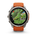 A Garmin fēnix 9 Pro inReach multisport GPS smartwatch with an orange band displays a detailed topographic map showing contour lines, place names, a red navigation arrow, and distance markings. The robust design features a metallic bezel with multiple buttons, highlighting its advanced satellite connectivity and precise navigation capabilities.