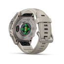 Back view of the Garmin fēnix 9 multisport GPS smartwatch in beige, highlighting the glowing green sensor on the case and the flexible silicone strap with a metal buckle.