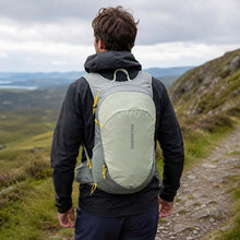 Person hiking with a green Salomon backpack on a mountain trail