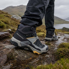 Person wearing Salomon hiking boots on a mountain trail with a lake in the background.