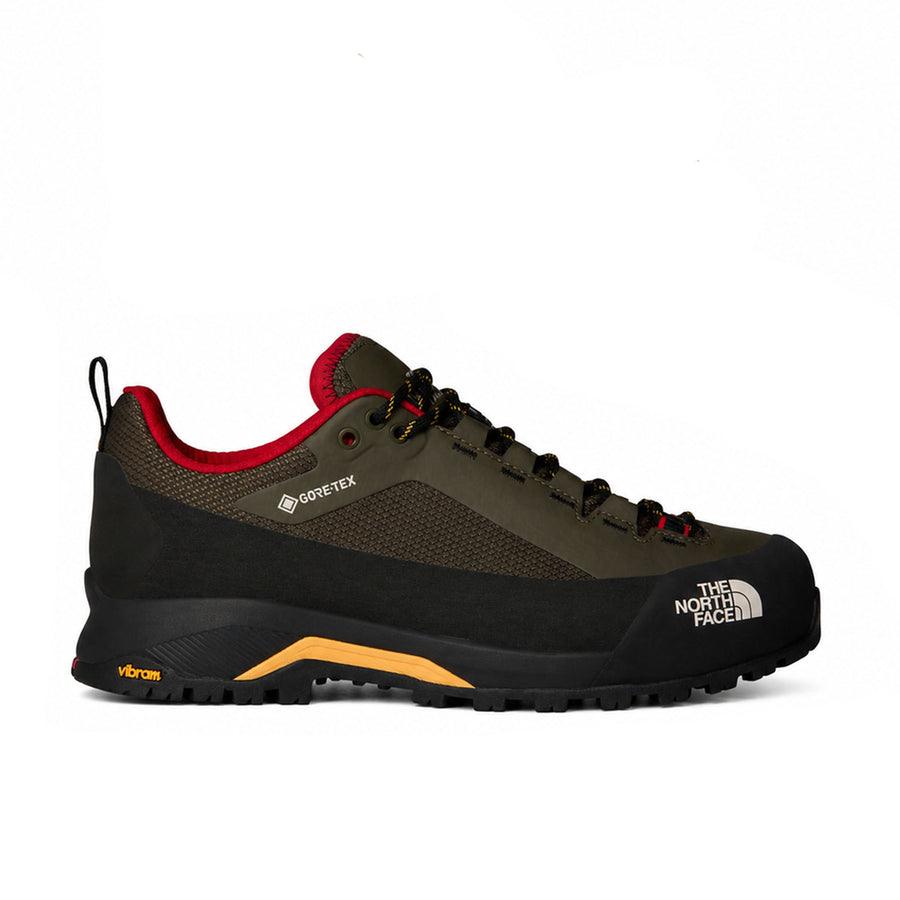 A single The North Face hiking shoe shown in profile against a white background. The shoe features an olive green and black upper with a red lining, black laces, a black sole, and a yellow Vibram logo on the midsole.