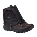 A pair of Trekmates Glenmore GORE-TEX Ankle Gaiters in black, attached to brown hiking boots and designed for superior trail protection against water and debris, displayed on a white background.