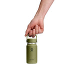 A hand holding a green Hydro Flask Micro Hydro Mini Bottle by its handle, isolated on a white background. This compact and insulated bottle from Hydro Flask is leakproof and ideal for staying hydrated on the go.