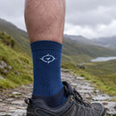 Person wearing blue socks with a logo on a mountain path