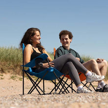 Two people sitting on folding chairs on a beach
