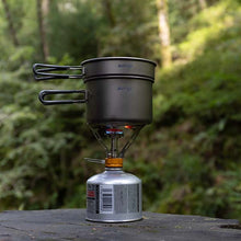 Portable camping stove with two pots on a blurred natural background